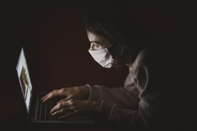 pesso usa máscara cirúrgica enquanto usa computador